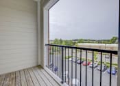 Thumbnail 20 of 30 - A balcony with a black railing overlooks a parking lot.