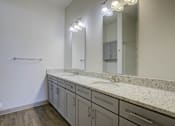 Thumbnail 27 of 30 - A bathroom with a marble countertop and a large mirror.