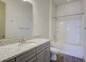 Thumbnail 2 of 30 - A white bathroom with a marble counter top and a walk in shower.