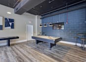 Thumbnail 11 of 30 - A pool table is in the middle of a room with a bench and a bar stool.