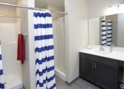 Thumbnail 26 of 32 - a bathroom with black cabinets and a blue and white shower curtain