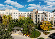 Thumbnail 20 of 36 - A large apartment complex with a courtyard and trees.