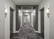 Thumbnail 11 of 36 - A long hallway with doors on both sides and lights on the ceiling.