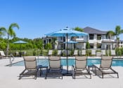Thumbnail 27 of 43 - a pool with chairs and umbrellas and a house in the background