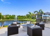 Thumbnail 32 of 43 - a patio with chairs and a fire pit overlooking a pond and a fountain