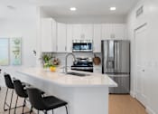 Thumbnail 42 of 43 - a kitchen with a large island and a stainless steel refrigerator