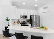 Thumbnail 1 of 43 - a kitchen with a large island with black chairs and a stainless steel refrigerator