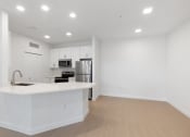Thumbnail 22 of 43 - a white kitchen with a large island and a stainless steel refrigerator