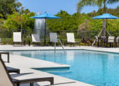Thumbnail 26 of 43 - a pool with chairs and umbrellas and a water fountain