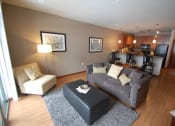 Thumbnail 16 of 21 - a living room with a couch and a chair and a kitchen