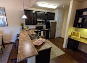 Thumbnail 25 of 34 - A kitchen with a granite countertop and black cabinets. at The Villas at Nature Walk, Huntsville, Alabama
