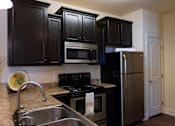 Thumbnail 29 of 34 - A kitchen with black cabinets and stainless steel appliances. at The Villas at Nature Walk, Huntsville, AL, 35824