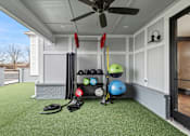 Thumbnail 43 of 52 - A garage with a white ceiling and a green artificial turf floor with a black bag and a pair of black shoes on it at Ovation at Town Madison, Alabama, 35758