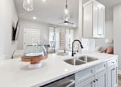 Thumbnail 37 of 52 - A modern kitchen with a white countertop and grey cabinets at Town Madison, Madison