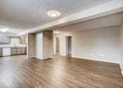 Thumbnail 2 of 12 - A spacious room with wooden flooring and white walls.