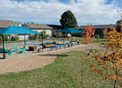 Thumbnail 9 of 12 - A playground with a blue umbrella and a slide.