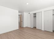 Thumbnail 12 of 19 - a bedroom with white walls and wood flooring and white closets