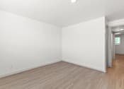 Thumbnail 11 of 19 - an empty living room with white walls and wood flooring