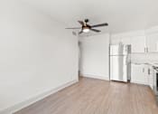 Thumbnail 9 of 19 - an empty living room with a ceiling fan and a refrigerator