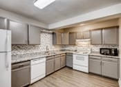Thumbnail 1 of 12 - A kitchen with white appliances and brown cabinets.