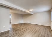 Thumbnail 3 of 12 - A room with wooden flooring and white walls.