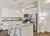 Thumbnail 10 of 15 - 2 BR Apartments in Vernon Hills, IL - The Oaks of Vernon Hills - Kitchen aith White Cabinets, Granite-Style Countertops, Island with Barstools, and Appliances.
