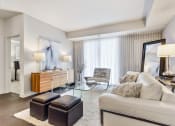 Thumbnail 11 of 15 - Vernon Hills, IL Apartments - The Oaks of Vernon Hills - Large Living Room With High Ceilings, Wood-Inspired Plank Flooring, Area Rug, Couch, Chair, Stools, And Access To Patio Or Balcony Area Via Sliding Glass Door