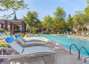Thumbnail 3 of 20 - Townhomes in Aurora, IL for Rent - Kirkland Crossing - Pool with Sun Lounge Chairs, Trees, and Potted Plants