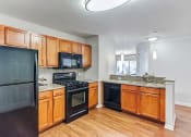 Thumbnail 19 of 20 - Aurora IL Townhomes - The Apartments at Kirkland Crossing - Spacious Kitchen with Wood Cabinets, Granite Countertops, and Black Appliances