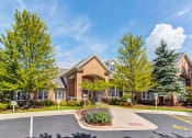 Thumbnail 20 of 20 - Aurora Apartments for Rent - The Apartments at Kirkland Crossing - Exterior Apartment Building with Tall Trees and Empty Parking Lot