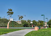 Thumbnail 21 of 30 - A park with a basketball court and a green lamp post.