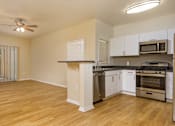 Thumbnail 18 of 30 - A spacious kitchen with white cabinets and stainless steel appliances.