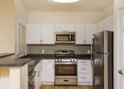 Thumbnail 17 of 30 - A kitchen with white cabinets and a black countertop.