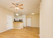 Thumbnail 11 of 30 - A room with a ceiling fan and wooden floors.