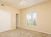 Thumbnail 13 of 30 - A room with a white door and a window with a view of trees and a house.