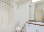 Thumbnail 14 of 30 - A white bathroom with a toilet, sink, and bathtub.