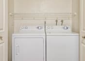 Thumbnail 8 of 30 - Two white front loading washing machines in a laundry room.