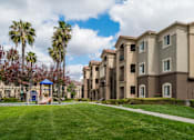 Thumbnail 7 of 30 - A row of apartment buildings with a playground in the foreground.