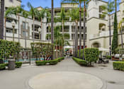 Thumbnail 7 of 30 - A courtyard surrounded by palm trees and buildings.