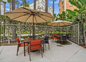 Thumbnail 5 of 30 - A patio with a table and chairs under umbrellas.