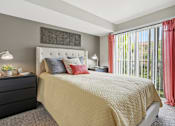 Thumbnail 11 of 30 - A bedroom with a large bed and a black dresser.