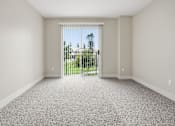 Thumbnail 20 of 30 - A room with a carpeted floor and a sliding glass door leading to a backyard.