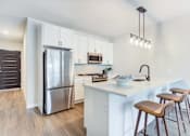 Thumbnail 2 of 19 - a kitchen with a large island with stools and a stainless steel refrigerator