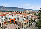 Thumbnail 2 of 30 - A large white building with a red roof is surrounded by mountains.