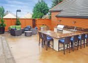 Thumbnail 25 of 31 - 2-Bedroom Apartments In Mountain Park, OR - MiLO - BBQ Area With Outdoor Couch And Armchairs, Grill Station, Sink, And Kitchen Counter With Seating.
