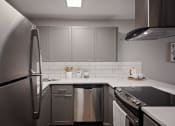 Thumbnail 2 of 31 - Apartments for Rent in Mountain Park - MiLO at Mountain Park - Chef-Grade Kitchen, with White Countertops and Backsplash, Grey Cabinetry, Black Electric Stovetop, and a Refrigerator.
