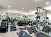 Thumbnail 10 of 14 - A spacious gym with a variety of equipment including treadmills, weight benches, and dumbbells.
