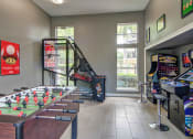Thumbnail 4 of 25 - Alpharetta Apartments – The Ascent at Windward – Game room arcade with foosball table and other arcade games