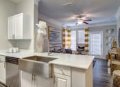 Thumbnail 5 of 25 - Pet-Friendly Apartments in Alpharetta, GA – The Ascent at Windward – view of living room from the kitchen with hardwood floors, ceiling fan and lots of light