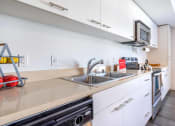 Thumbnail 6 of 18 - One Bedroom Apartments in Green Lake Seattle WA - Circa Green Lake - Kitchen with White Cabinets, Beige Countertops, and Stainless Steel Appliances.
